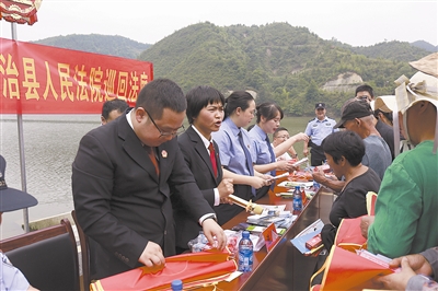 法院干警及相关部门工作人员对群众进行生态环境保护普法教育。